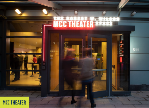 MCC Theater: Two people walking into the theater with Neon lighting that says "MCC Theater".